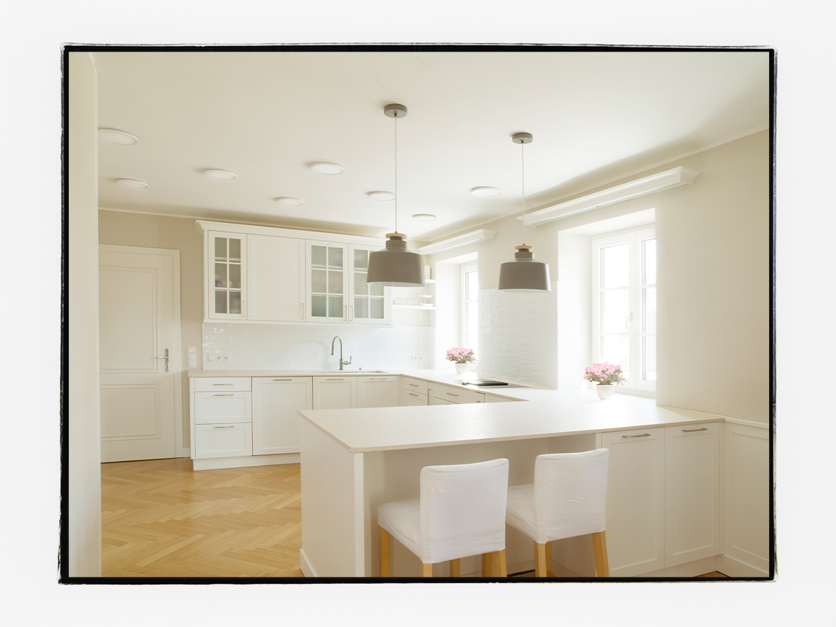 Küche im klassischen Landhaus-Stil mit weißen Küchenschränken und einer beigen Dekton-Arbeitsplatte